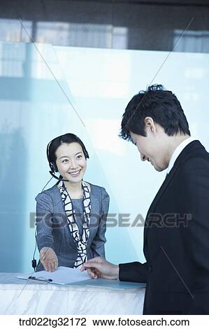 Stock Image - A receptionist guiding a businessman . Fotosearch