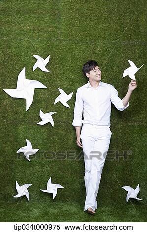 Stock Photography - A standing man with white pinwheels. Fotosearch