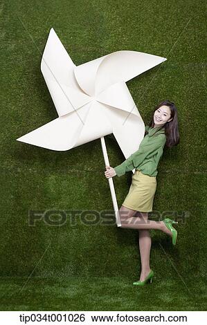 Stock Photograph - A standing woman with a big white pinwheel. Fotosearch