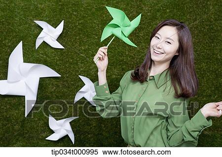 Stock Photography - A standing woman with green and white pinwheels. Fotosearch