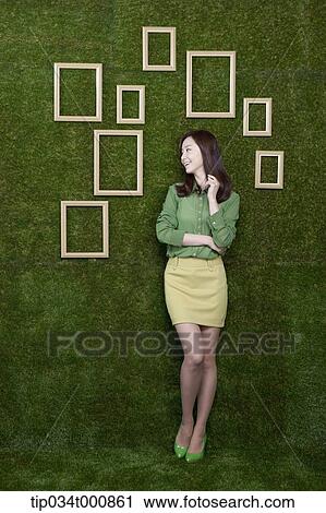 Stock Image - A woman and wooden frames on the green wall. Fotosearch