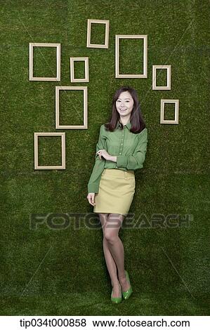 Stock Photo - A woman and wooden frames on the green wall. Fotosearch