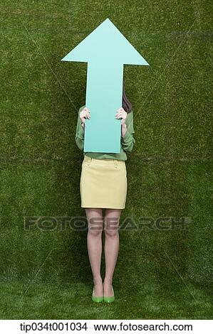 Picture - A woman behind a green arrow. Fotosearch