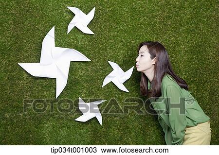 Stock Image - A woman blowing the white pinwheels. Fotosearch