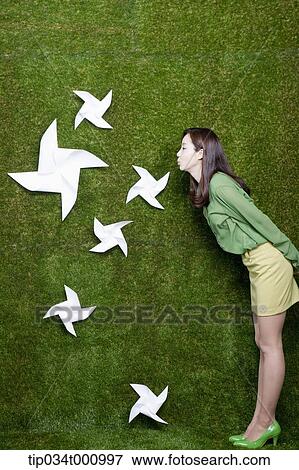 Stock Photo - A woman blowing the white pinwheels. Fotosearch