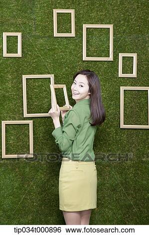 A woman holding a frame from the green wall View Large Photo Image Stock Photograph - A woman holding a frame from the green wall. Fotosearch
