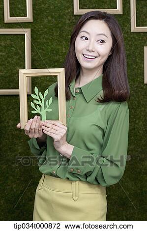 A woman holding a frame of green tree View Large Photo Image Stock Image - A woman holding a frame of green tree. Fotosearch