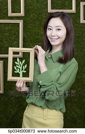 Stock Image - A woman holding a frame of green tree. Fotosearch