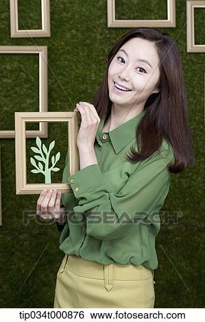 A woman holding a frame of green tree View Large Photo Image Stock Photograph - A woman holding a frame of green tree. Fotosearch