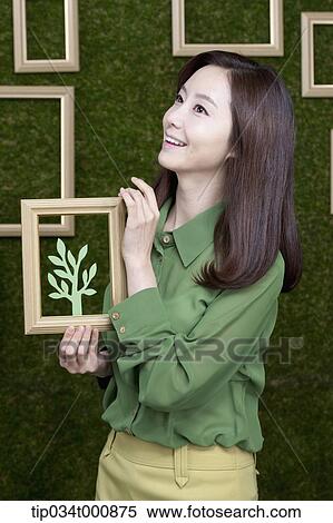 Stock Photography - A woman holding a frame of green tree. Fotosearch