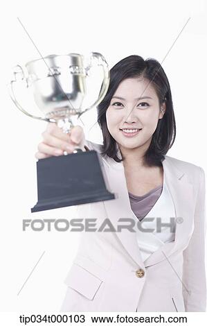Stock Image - A woman holding a trophy. Fotosearch