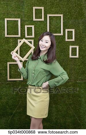 A woman holding a wooden frame from the green wall View Large Photo Image Stock Photo - A woman holding a wooden frame from the green wall. Fotosearch
