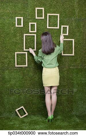 A woman looking at the frames on the green wall View Large Photo Image Stock Image - A woman looking at the frames on the green wall. Fotosearch