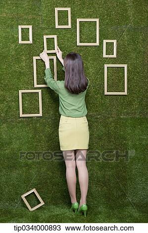 A woman putting the frame on the green wall View Large Photo Image Stock Image - A woman putting the frame on the green wall. Fotosearch