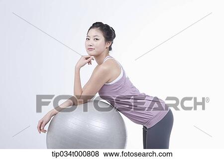 Stock Photo - A woman resting on a gym ball. Fotosearch