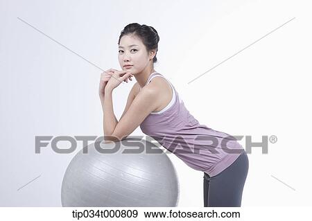 Stock Photo - A woman resting on a gym ball. Fotosearch