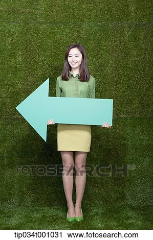 Stock Image - A woman standing with a green arrow. Fotosearch