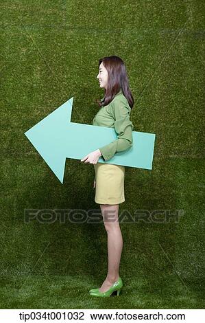 Stock Image - A woman standing with a green arrow. Fotosearch