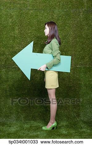 Stock Image - A woman standing with a green arrow. Fotosearch