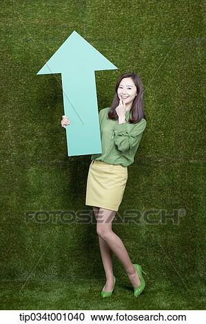 Stock Image - A woman standing with a green arrow. Fotosearch