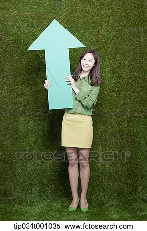 Stock Photography - A woman standing with a green arrow. Fotosearch