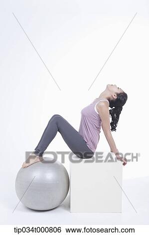 Stock Photograph - A woman stretching with a gym ball. Fotosearch