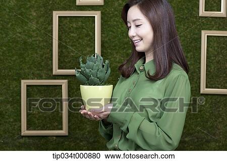 Stock Image - A woman with a green cactus pot. Fotosearch