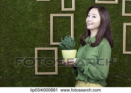 Stock Image - A woman with a green cactus pot. Fotosearch