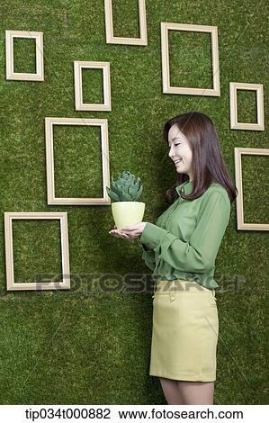 Stock Image - A woman with a green cactus pot. Fotosearch