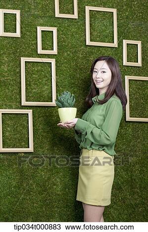 Stock Image - A woman with a green cactus pot. Fotosearch