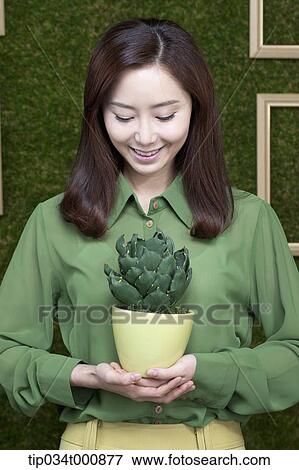 Stock Photo - A woman with a green cactus pot. Fotosearch