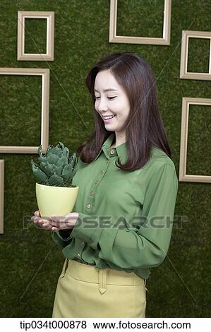 Stock Photo - A woman with a green cactus pot. Fotosearch