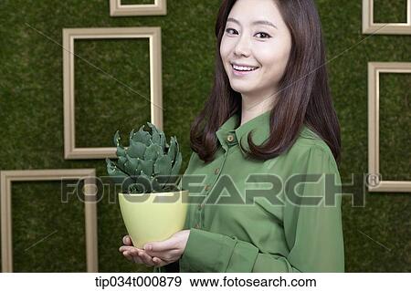 Stock Photo - A woman with a green cactus pot. Fotosearch
