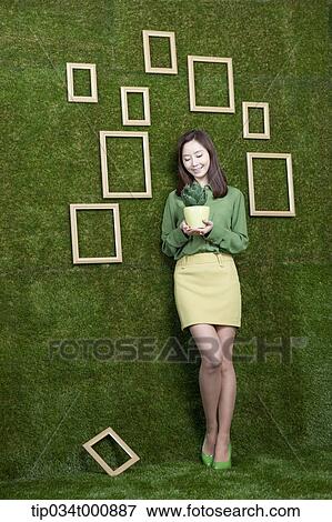Stock Photo - A woman with a green cactus pot. Fotosearch