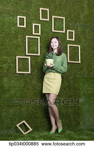 Stock Photography - A woman with a green cactus pot. Fotosearch