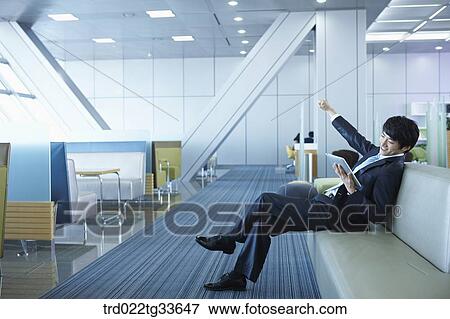 Stock Photo - An excited businessman with the tablet PC. Fotosearch