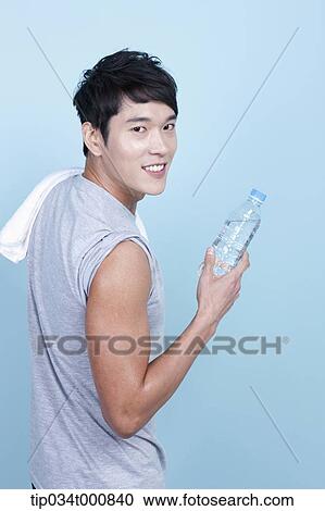 Stock Image - An exercising man with a bottle of water and towel. Fotosearch