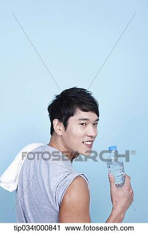 Stock Image - An exercising man with a bottle of water and towel. Fotosearch