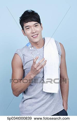 Stock Photo - An exercising man with a bottle of water and towel. Fotosearch