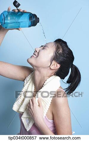 Stock Photo - An exercising woman pouring the water on her face. Fotosearch