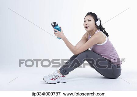 An exercising woman taking a break with music View Large Photo Image Stock Photo - An exercising woman taking a break with music. Fotosearch