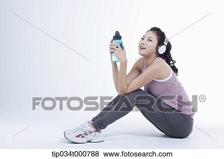 Stock Photo - An exercising woman taking a break with music. Fotosearch