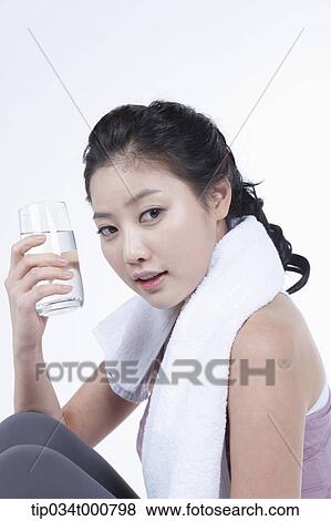 Stock Photo - An exercising woman taking a break with water. Fotosearch