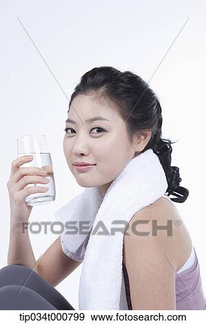 Stock Photo - An exercising woman taking a break with water. Fotosearch