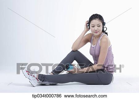 Stock Photograph - An exercising woman taking a break with music. Fotosearch