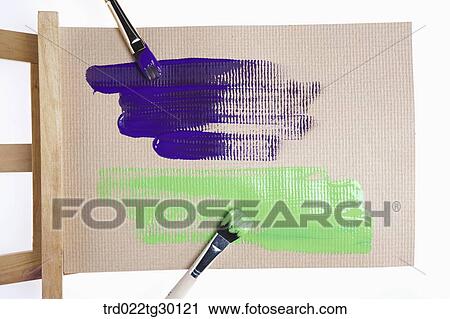 Stock Image - Blue and green paint with paintbrushes on easel. Fotosearch