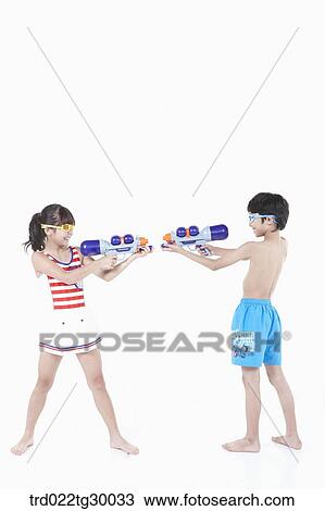 Stock Image - boy and girl are holding water guns on each other. Fotosearch