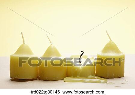 Stock Photograph - Burned yellow candle with other yellow candles in a row. Fotosearch
