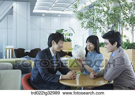 Stock Photo - Businessmen having a talk with the globe. Fotosearch