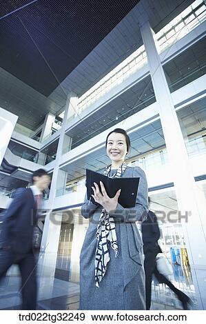 Stock Photo - Businessmen holding the planner and passing by in the lobby. Fotosearch